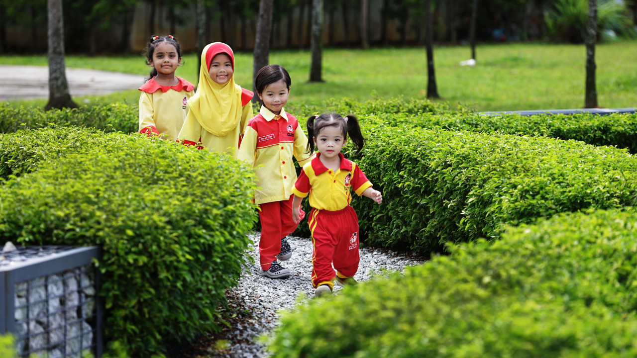 Four Little Ones Eduworld children walking through a garden during an outdoor learning activity